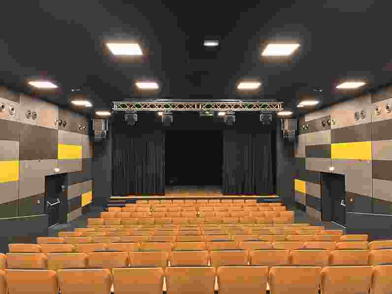 Black suspended acoustic ceiling and acoustic wall panels in dark grey, light grey and yellow in concert and theatre hall