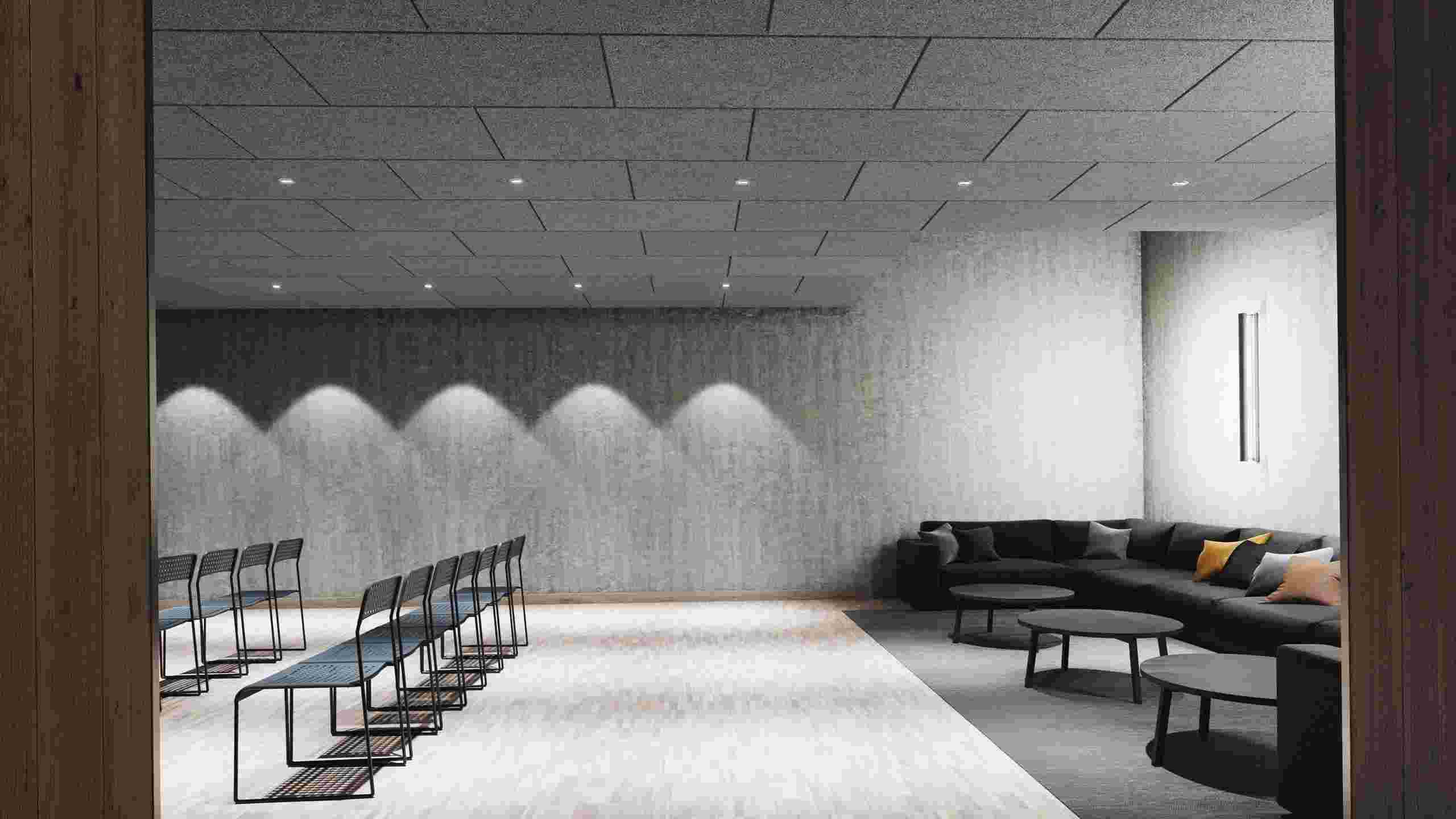 Šedý, akustický strop z dřevité  vlny v konferenční místnosti se židlemi v řadách a rohovou pohovkou a třemi konferenčními stolky v zadní části místnosti
